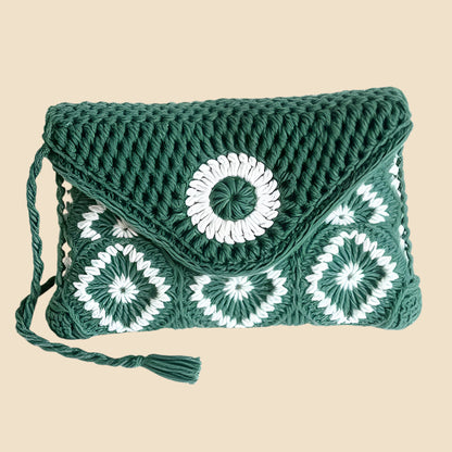 Green and white crochet handbag with circular patterns on a pink background