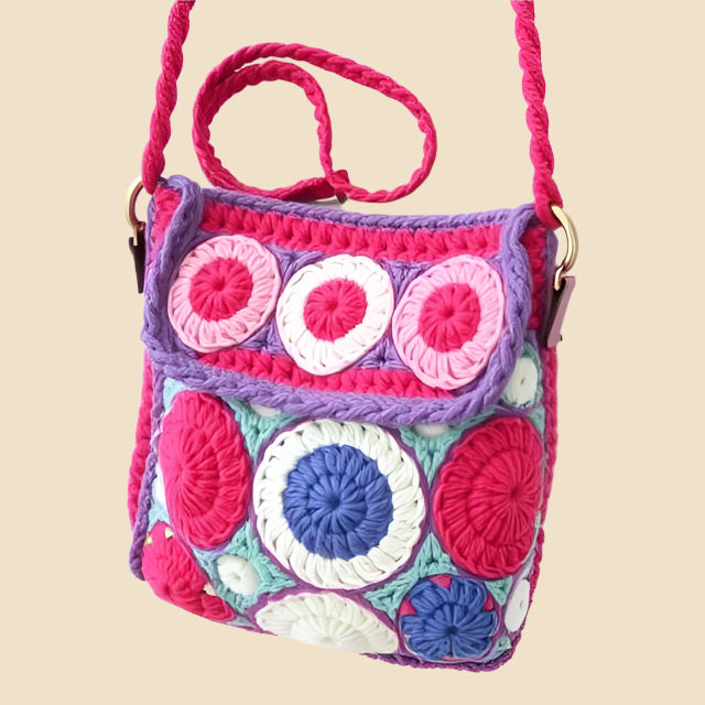 Colorful crochet bag with owl design on a pink background