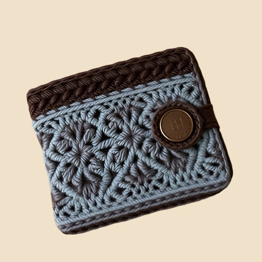 Crocheted wallet with brown flap and button on a pink background