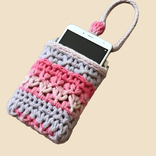 Crocheted phone pouch with pink and gray pattern on a pink background