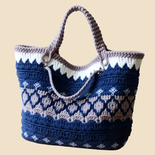 Blue, grey and white crochet tote with circular patterns on a pink background