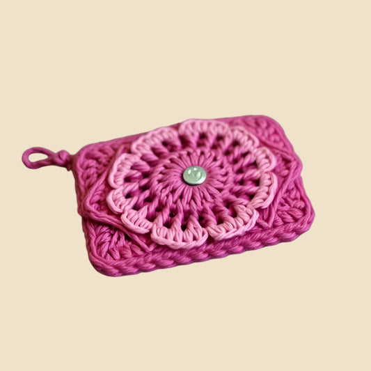 Pink crocheted pouch with a button on a pink background